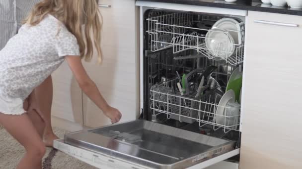Una bambina, insieme a sua madre, mette i piatti sporchi in lavastoviglie. - Filmati, video