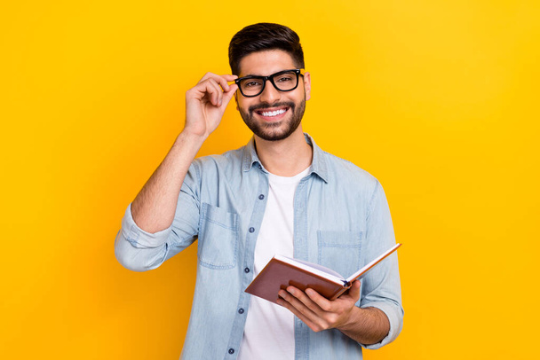 Photo of cheery hispanic man hold copybook author have inspiration wear trendy denim outfit eyeglasses isolated on yellow color background. - Fotó, kép