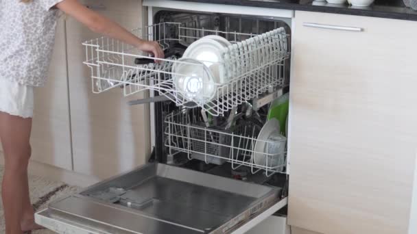 Μια μητέρα με μια μικρή κόρη φορτώνει βρώμικα πιάτα στο πλυντήριο πιάτων στο σπίτι το πρωί. - Πλάνα, βίντεο