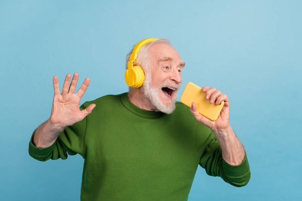 Portrait of excited crazy person hold telephone singing voice recording application isolated on blue color background. - Photo, Image