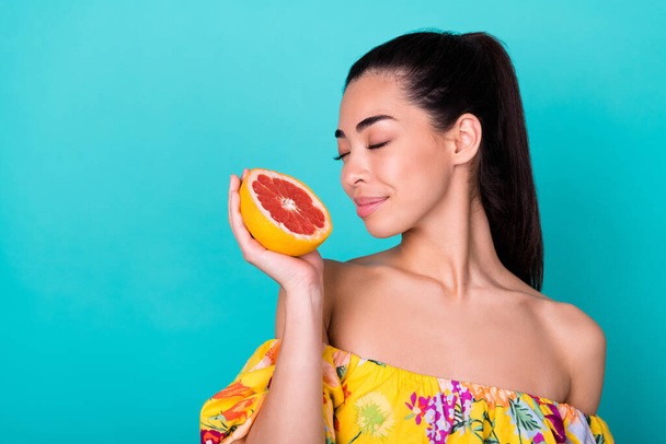 Closeup photo of young japanese pretty girl first time smell holding hands grapefruit isolated on cyan color background. - Photo, image