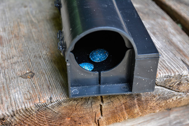 Eine schwarze Kunststoff-Rattenfalle auf Betonboden. Ködergiftbox für Ratte. Eine schwarze Kunststoff-Rattenfalle (Köderbox). Image der Schädlingsbekämpfung. - Foto, Bild