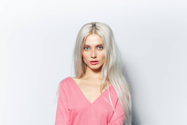Студийный портрет молодой блондинки красивая девушка, в пастельно-розовой рубашке на белом фоне. - Фото, изображение