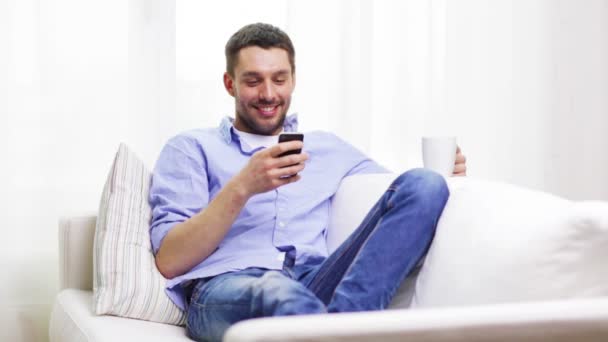 smiling man with smartphone at home - Felvétel, videó