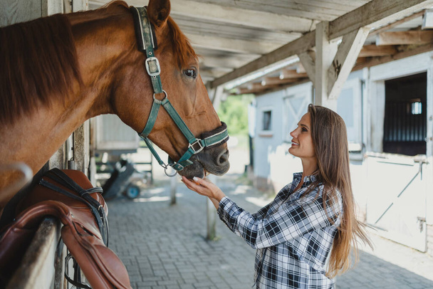 Jeune femme dans une écurie avec son cheval - Photo, image
