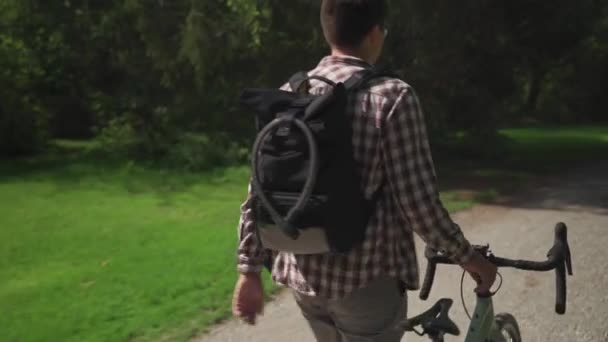 Messenger op de fiets met rugzak en fietsslot uitzicht op de rug gaat duwen een fiets in Duitsland. Een fietspendelaar loopt met de fiets mee. De fiets is kapot en hij rolt hem naast hem..  - Video
