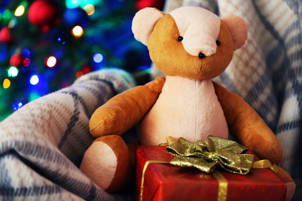 Teddy bear and gift box in rocking chair on Christmas tree background - Photo, Image