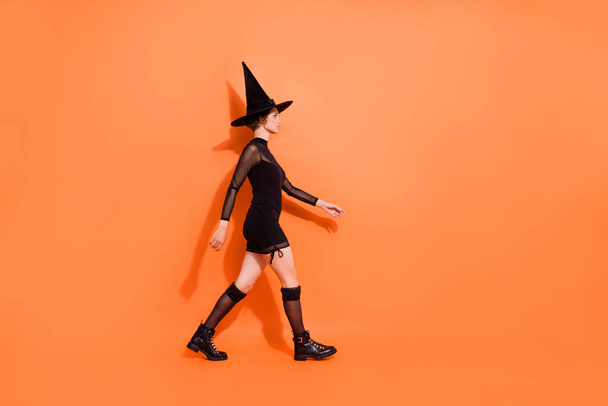 Full size profile photo of pretty mysterious girl walking isolated on orange color background. - 写真・画像