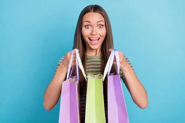 Photo of optimistic impressed girl with long hairstyle wear striped t-shirt happy to buy new clothes isolated on blue color background. - Фото, изображение