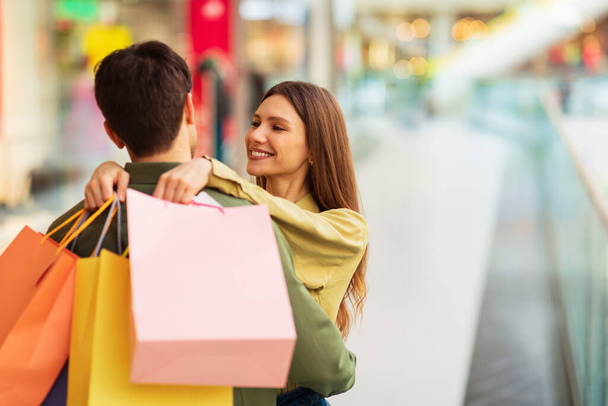 Μεγάλη προσφορά για ψώνια. Σύζυγος αγκαλιάζει σύζυγος κρατώντας τσάντες Shopper Αγοράζοντας νέα ρούχα μαζί στο σύγχρονο εμπορικό κέντρο. Sales Season Διαφήμιση Concept. Επιλογή εστίασης - Φωτογραφία, εικόνα