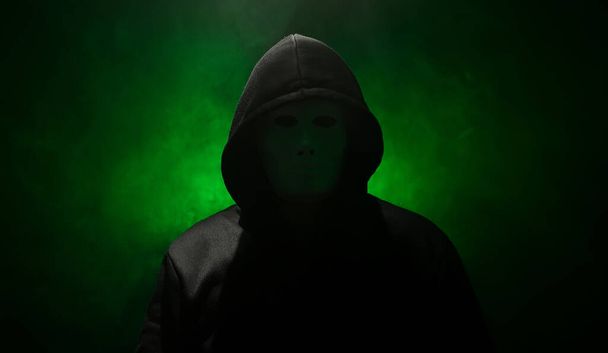 Uomo mascherato con cappuccio su sfondo verde. - Foto, immagini