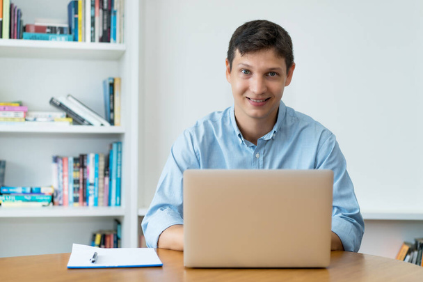 Naurava valkoihoinen mies töissä tietokoneella toimistossa - Valokuva, kuva