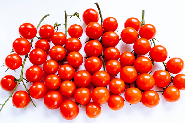 白い背景に緑色の茎を持つ新鮮な赤いチェリートマトの束。新鮮な赤鮮やかな色のトマトのトップビュー - 写真・画像