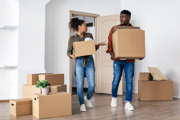 Couple noir mécontent portant des boîtes mobiles en carton entrant dans une mauvaise nouvelle maison. Acheteurs immobiliers mécontents d'avoir des problèmes avec la propriété. Prise de vue complète - Photo, image