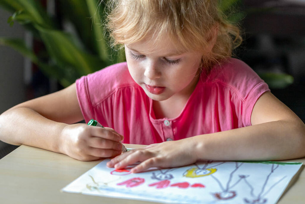 Menina desenhando um quadro com marcadores coloridos. Criança, sentada na mesa, aprendendo a desenhar. - Foto, Imagem