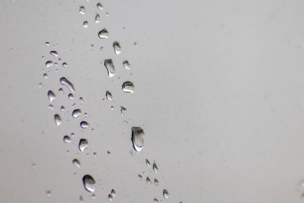 Βροχερές σταγόνες ημέρας στο παράθυρο ως χαλαρωτική υφή φόντου για την εποχή του φθινοπώρου και του φθινοπώρου δείχνει βροχή και σταγονίδια νερού που πιτσιλίζονται στην επιφάνεια του παραθύρου με βροχερή υφή καιρικές συνθήκες σε διάθεση κατάθλιψης - Φωτογραφία, εικόνα