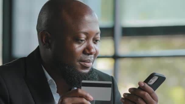 Afrikaanse klant zakenman invoeren van creditcardgegevens gebruik beveiligingscode voor elektronisch geld overdracht pijn online diensten veilig betalen in mobiele telefoon bankieren app moderne tech kopen afstand gemakkelijk - Video