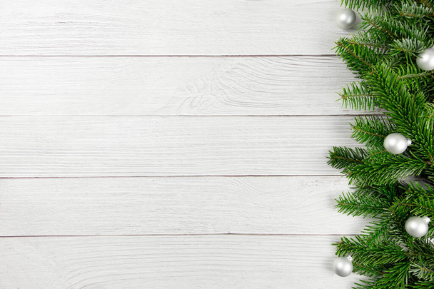 Kerst platte lay achtergrond met sparren takken en zilveren ballen decoraties op witte houten achtergrond. Bovenaanzicht. Kopieerruimte. - Foto, afbeelding