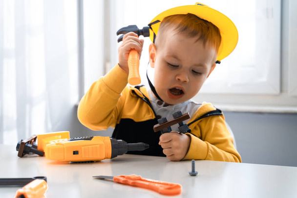 Child play with work tools at home, dreams to be an engineer. Little boy builder. Education, and imagination, purposefulness concept. Kid and hummer. - Fotoğraf, Görsel