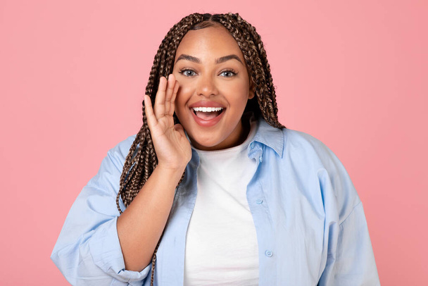 Happy Oversized Black Lady Shouting Holding Hand in der Nähe von geöffnetem Mund Ankündigung eines großen Angebots lächelnd in die Kamera stehen im Studio über rosa Hintergrund. Werbebanner - Foto, Bild