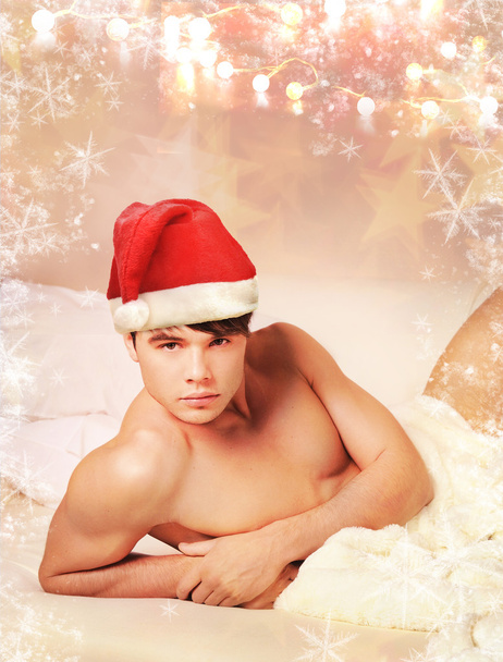 Sexy man in santa hat lying on a bed. - Fotoğraf, Görsel