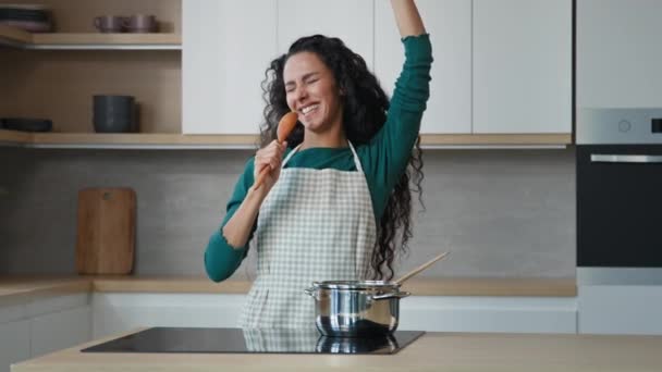Onnellinen energinen latino nainen laulaa laulun lusikka tanssia kovaa popmusiikkia kotona nauttia kotimaisen karaoke tuntuu stressiä vapaa leikkisä aikaa yksin hauskaa moderni keittiö ilo kokata terveellistä ruokaa - Materiaali, video