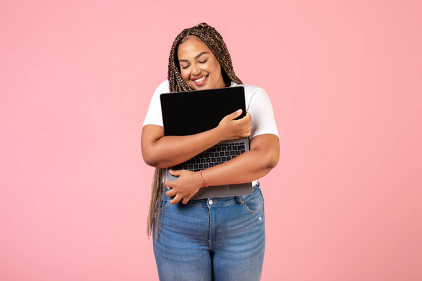 Happy Black Freelancer Mujer Abrazando Computadora portátil Publicidad Sitio web De pie sobre Pink Studio Fondo. Trabajo independiente y concepto de tecnología de Internet - Foto, Imagen