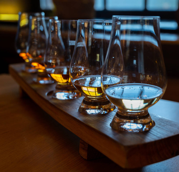 Flight of single malt scotch whisky in glasses served in bar in Edinburgh, UK, tasting of dram of whiskey - Fotó, kép