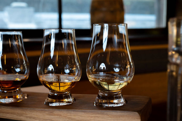 Flight of single malt scotch whisky in glasses served in bar in Edinburgh, UK, tasting of dram of whiskey - 写真・画像