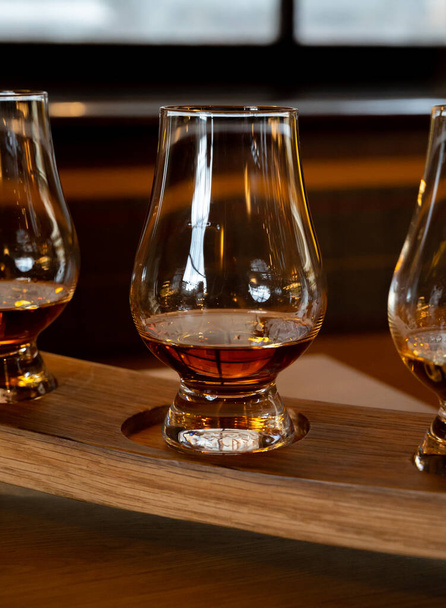 Flight of single malt scotch whisky in glasses served in bar in Edinburgh, UK, tasting of dram of whiskey - Foto, imagen