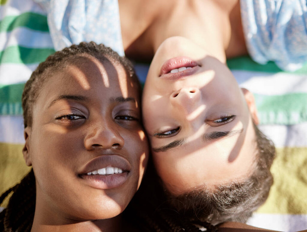 Summer, selfie and a girl and girlfriend at the beach lying on a towel, shadow of hands in face. Pride, lgbt and young woman best friends or lesbian couple relax in sun by the ocean on the weekend - Foto, Imagem