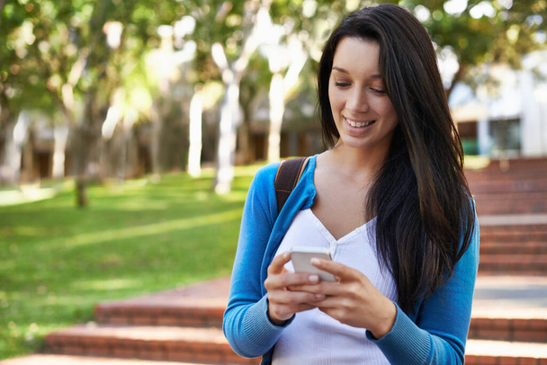 Keeping in touch while between classes...Cropped view of a college student sending a text while outdoors - Foto, imagen