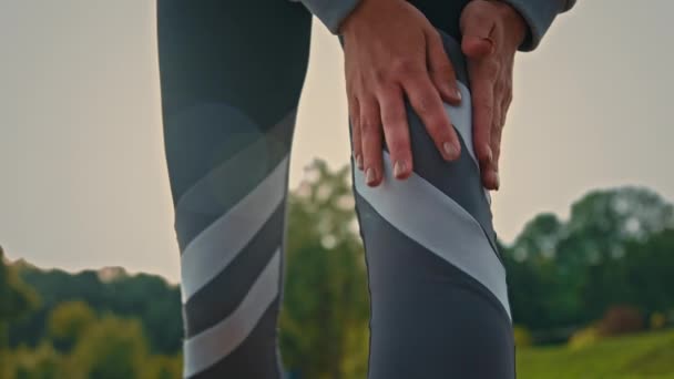 Cierre las piernas en traje gris deportista esbelta corredor atlético chica siente dolor de rodilla esguince músculos después de correr correr correr por la mañana sufren de artritis trauma masaje lesionado parte del cuerpo dañado - Imágenes, Vídeo