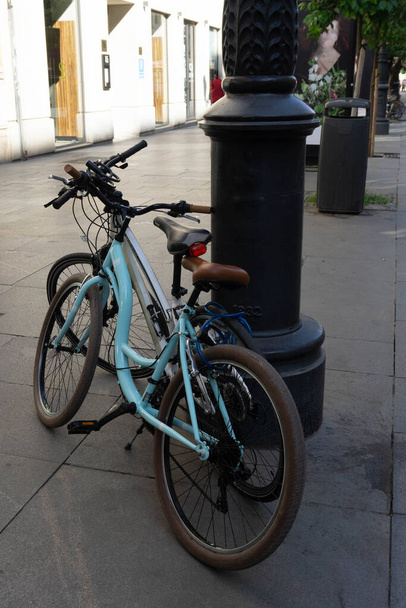 dvě jízdní kola podpořená pouliční lampou pro udržitelnou mobilitu ve městě - Fotografie, Obrázek