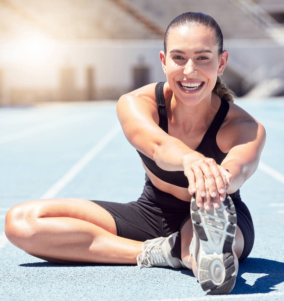 Happy fitness or sports woman stretching at stadium in sunshine lens flare for healthy lifestyle and wellness motivation. Young athlete runner on ground outdoor in trainer shoes for exercise training. - Photo, image