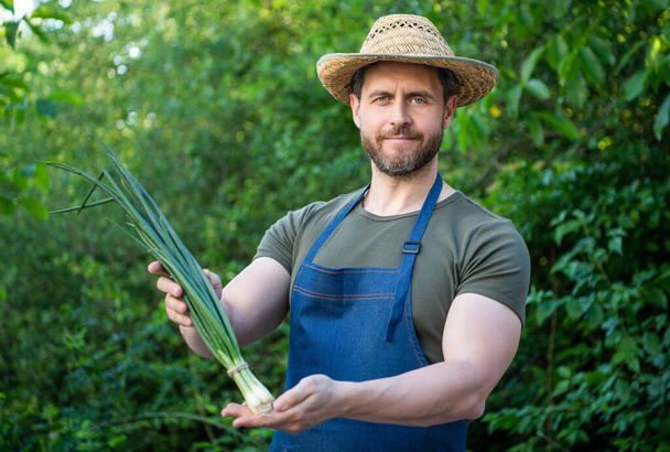 férfi agronómus szalma kalap zöld hagyma zöldség. - Fotó, kép