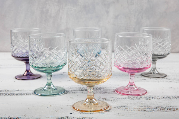 Set of six crystal juice glasses. A set of six vintage, multicolored, crystal glasses with a white stem on a light background. - Photo, Image