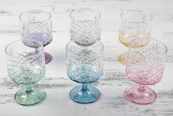 Set di sei bicchieri di succo di cristallo. Set di sei bicchieri in cristallo vintage multicolore con gambo bianco su fondo chiaro. - Foto, immagini