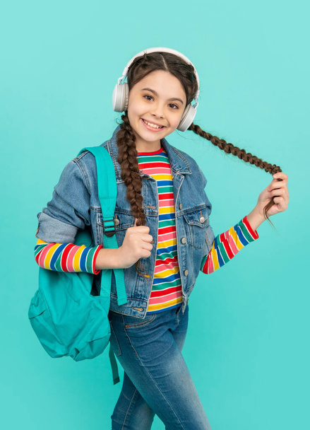Happy teenage girl listening to music in headphones blue background, education. Informal education. School education. - Foto, Imagem