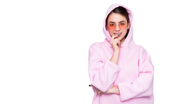 Happy fashion woman smiling keeping finger on lip in casual pink hoodie isolated on white. - Foto, imagen