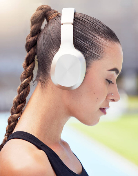 Woman runner listening to music on headphones training for fitness marathon or triathlon streaming radio audio. Girl sports athlete workout, running and mp3 song exercise for cardio at track stadium. - Photo, image