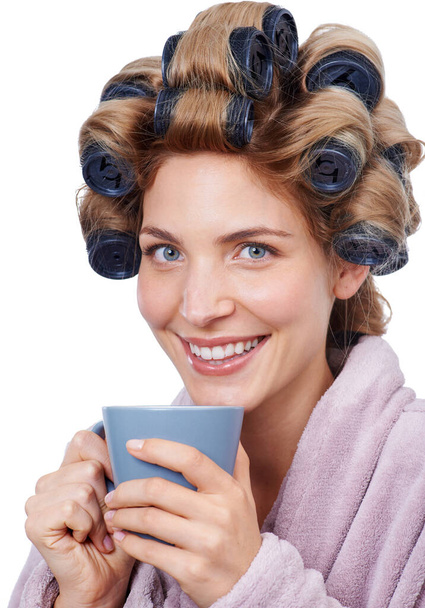 Everyone one needs help in the morning. Studio shot of a woman with curlers in her hair and wearing a robe drinking coffee - Foto, imagen