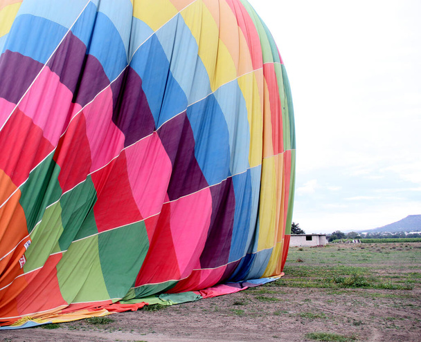 Inflationsprozess und Vorbereitung des Heißluftballons bei Sonnenaufgang auf den Flug bei bewölktem Himmel - Foto, Bild