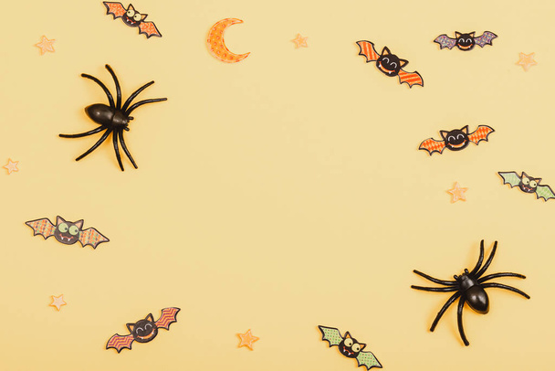 Halloween festive background with spiders and bats on yellow. Top view, flat lay, copy space. - Photo, Image