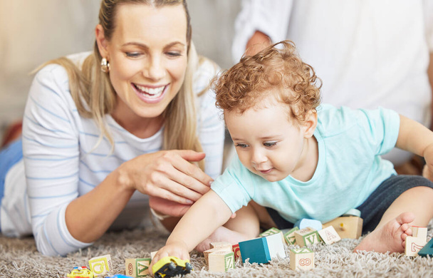 Mutter, Kind und spielendes Lernblockspielzeug auf dem Fußboden für die gemeinsame Lernzeit im Elternhaus. Junge, fürsorgliche und liebevolle Frau hilft Kleinkind bei kindlicher Entwicklung und Koordinationsfähigkeiten - Foto, Bild