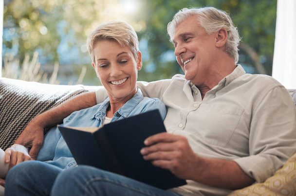 Senior, pension and reading couple with a happy smile at home on a lounge sofa. Love, calm and happiness mindset of a elderly couple with books together looking at pages of a book on a house couch. - Photo, Image