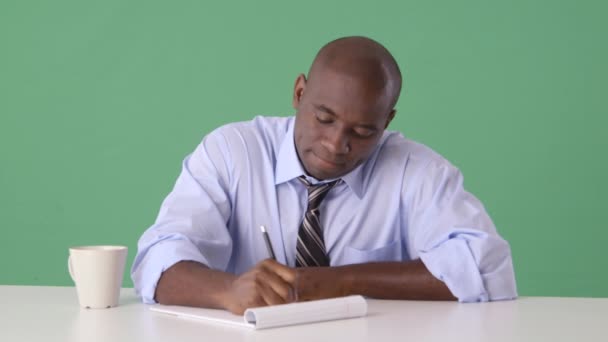 Afroamerikanischer Geschäftsmann, der am Schreibtisch arbeitet, wirft Papier weg - Filmmaterial, Video