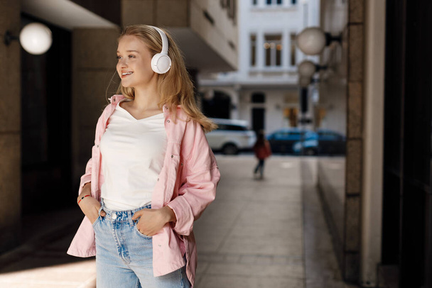 beautiful young woman with headphones outdoors. High-quality photo - Фото, изображение