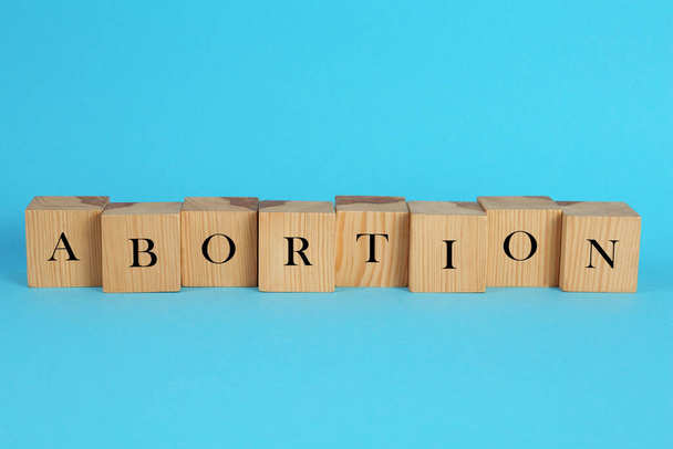 Word Abortion made of wooden cubes on light blue background - Photo, Image
