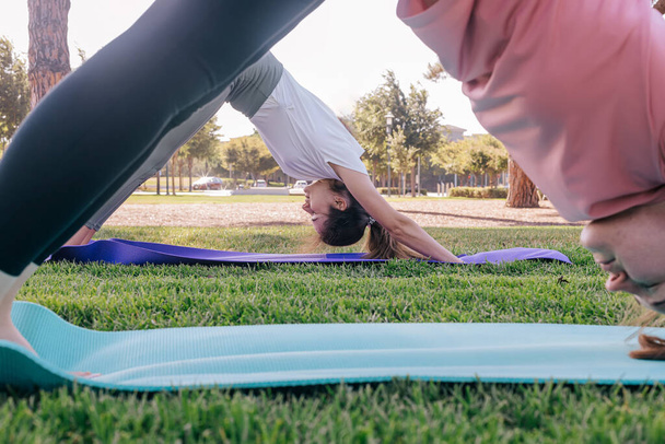 Two young women in the park doing yoga in the morning. Exercising outdoors, healthy lifestyle. - Foto, imagen